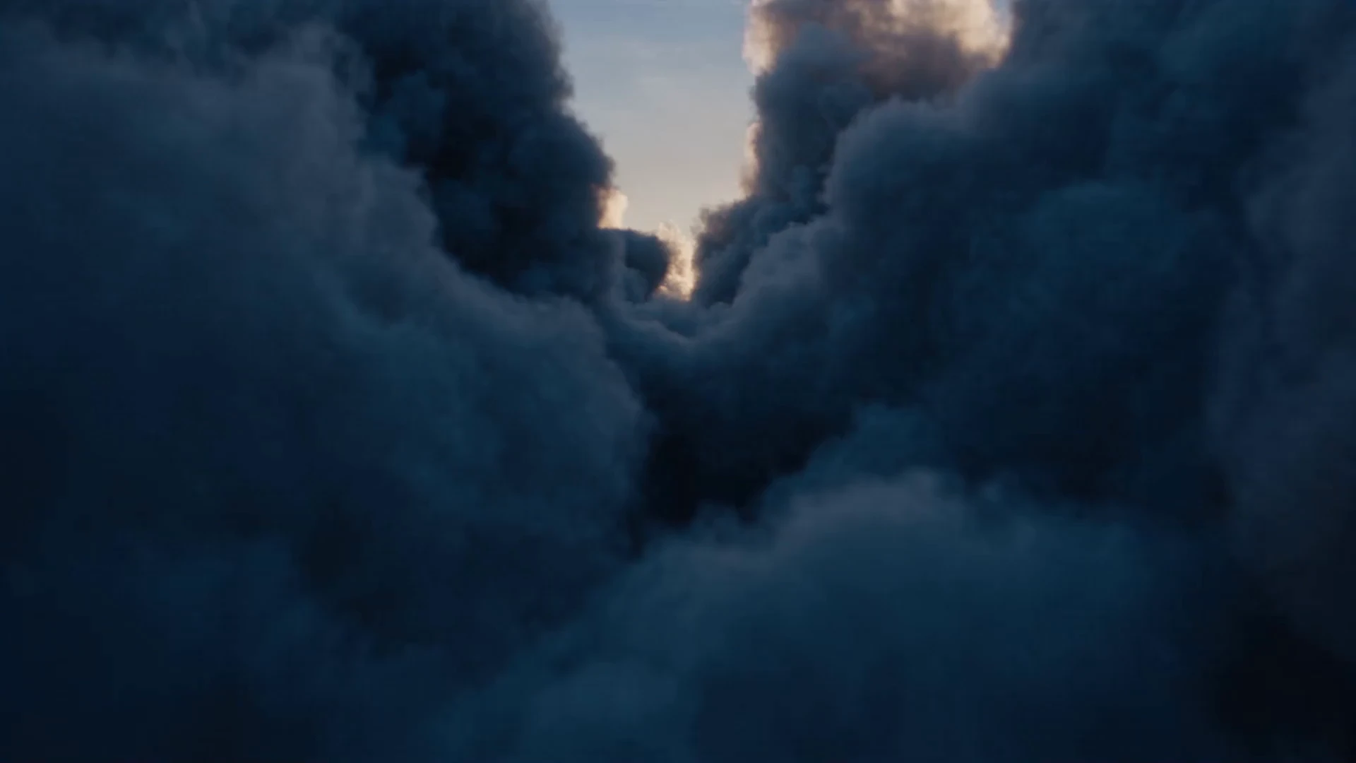 Dark sculptural clouds opening into silver sunlight